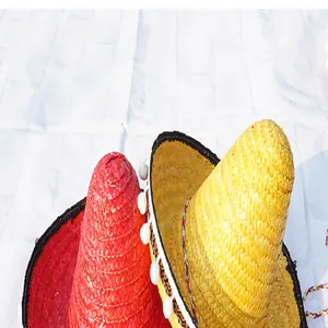 Close-up of Mexican straw sombrero hats with white pom-pom trim and colorful weave.