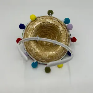 Close-up detail of a mini pet Mexican straw hat with colorful pom-poms and white headband