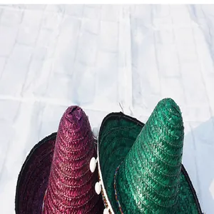 Detailed view of colorful purple and green Mexican straw hats with festive pom-poms