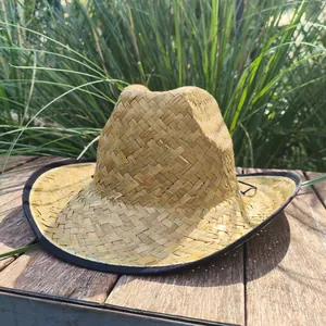 Close-up detail of a hand-woven Mexican straw cowboy hat featuring a black brim trim outdoors
