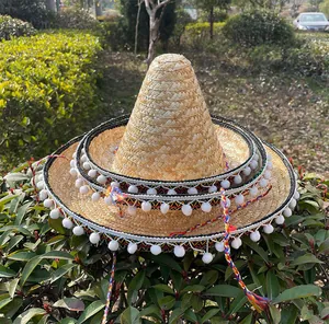 Drie verschillende maten Mexicaanse strohoeden met witte pompons en kleurrijke linten.