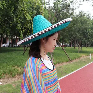 Close-up detail of a vibrant green Mexican straw sombrero hat with white pom-pom trim