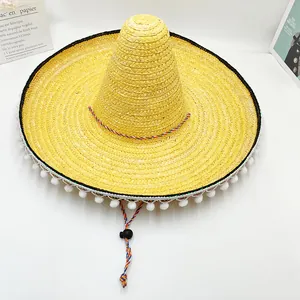 Vista detallada de un sombrero de paja mexicano amarillo con pompones blancos y cordón.