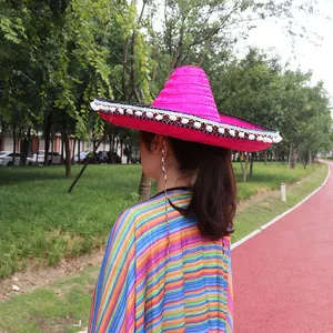 Rear view detail of a vibrant pink Mexican sombrero with white pom-pom trim worn outdoors