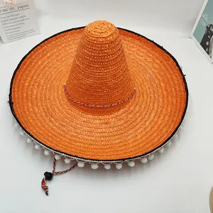 Vista detallada de un sombrero de paja mexicano naranja brillante con pompones blancos decorativos