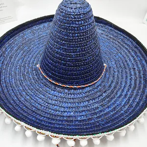 Primer plano de sombrero mexicano de paja azul con detalle de pompones blancos y cuerda