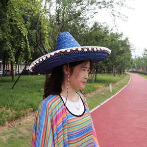 Side view of woman wearing a blue Mexican straw sombrero with pom-poms