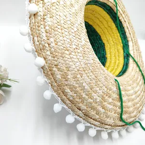 Close-up of Mexican straw hat brim with white pom-poms and green woven detail