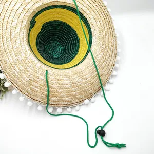 Detailed view of Mexican straw hat interior with green strap and pom-pom trim