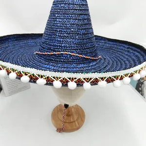 Vista detallada de un sombrero de paja mexicano azul con adornos coloridos y pompones blancos.