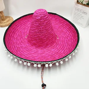 Primer plano de un sombrero de paja rosa brillante con pompones blancos y cinta