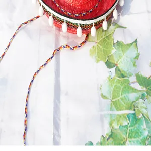 Macro view of red Mexican straw hat featuring white pompoms and colorful decorative weave patterns