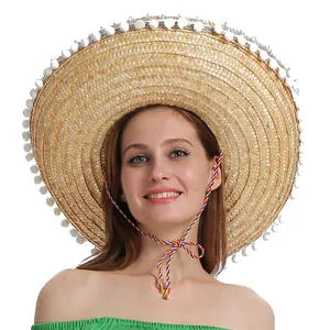 Gros plan d'un chapeau sombrero mexicain en paille avec pompons blancs et jugulaire.