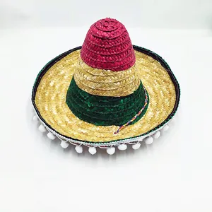 Close-up of a colorful Mexican woven straw hat featuring pom-pom trim and pink green bands