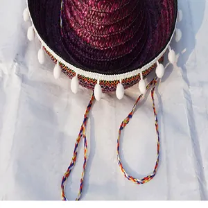 Detailed view of Mexican Sombrero straw hat featuring white pompoms and colorful braided straps
