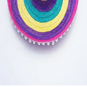 Close-up detail of a colorful Mexican straw hat brim with decorative white pom-poms
