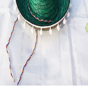 Close-up detail of a green Mexican straw hat with white pompoms and colorful trim