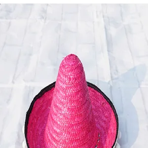 Detailed view of a vibrant pink Mexican straw hat with white pom-poms for parties.