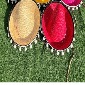 Top view detail of colorful Mexican straw hats with white pom-poms on green grass