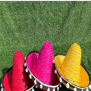 Close-up of three colorful Mexican sombreros with white pom-poms on green grass