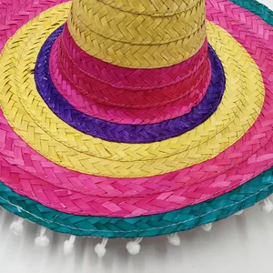Detailed view of colorful woven straw texture and white pom-pom trim on Mexican hat