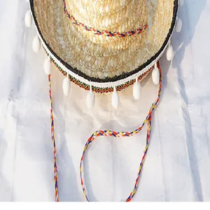 Close-up of Mexican straw hat with colorful braided trim and white pompoms.