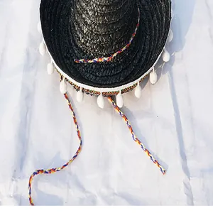 Detailed view of black Mexican sombrero with white pom-poms and colorful cords