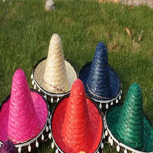 Detail view of colorful Mexican straw sombreros decorated with white pom pom trim.