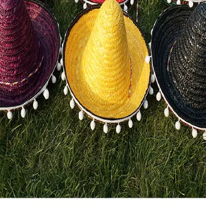 Close-up detail of colorful Mexican straw sombreros with white pom-pom trim on grass