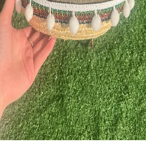 Detailed view of the colorful woven brim and white pom-poms of a Mexican straw hat.