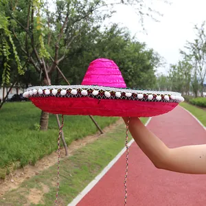 Side detail of a bright pink Mexican straw sombrero with white pompom fringe