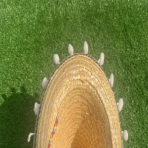 Close-up detail of a straw Mexican sombrero with white pompoms and colorful trim