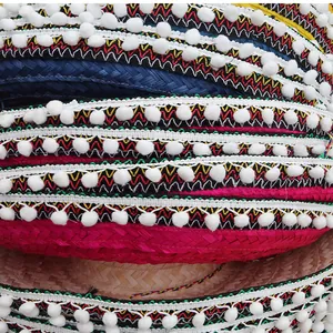 Detailed macro view of colorful Mexican straw hats featuring ethnic patterns and pom-pom fringe