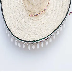 Close-up detail of Mexican carnival straw hat with white pom-poms and braided trim.