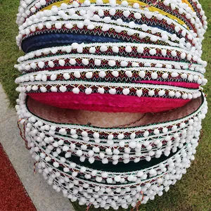 Colorful Mexican straw hats stack with white pom-pom fringe and ethnic patterns detail view.