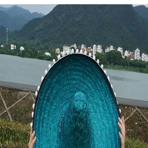 Detailed view of a teal Mexican woven straw hat with festive white pom-pom trim decoration