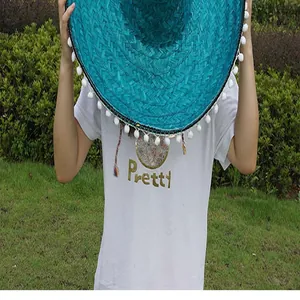 Detailed texture of a teal Mexican straw hat with white pom-pom trim for parties.