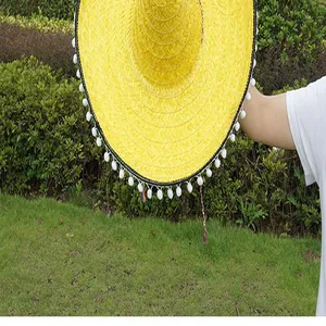 Detailed view of yellow Mexican straw hat with white pom-pom trim for parties