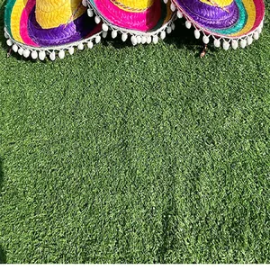Detailed view of mini Mexican straw hats with colorful weave and pompom trim on grass