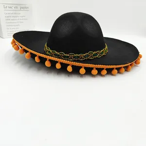 Macro detail of a black Mexican festival sombrero with orange pom-poms and gold trim