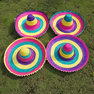 Four colorful Mexican sombreros with white pom-poms on a grass lawn for parties