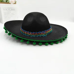 Detail view of a black Mexican sombrero with colorful embroidery and green pom-poms.