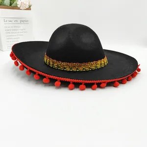 Detailed close-up of a black Mexican party hat featuring red pom-poms and gold trim