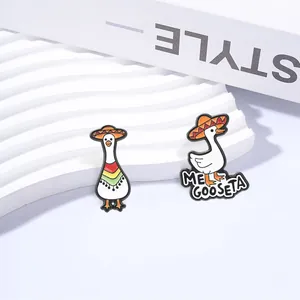 Detail of two white goose enamel pins wearing Mexican sombreros and colorful ponchos.