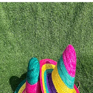 Vibrant multi-color woven straw Mexican sombreros on green artificial grass background