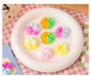 Colorful cat paw squishy stress relief toys displayed on a white plate with props.