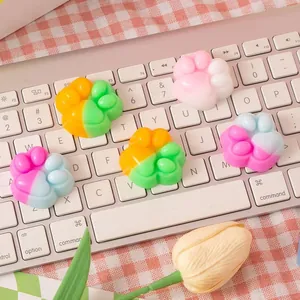 Colorful cat paw squishy stress relief toys displayed on a white laptop keyboard