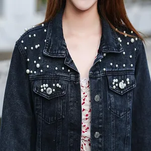 Detailed macro view of women's denim jacket with intricate pearl bead embellishments
