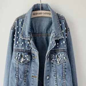 Close-up detail of women's short blue denim jacket featuring elegant white pearl beads
