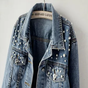 Detailed view of women's denim jacket with elegant pearl embellishments on shoulder